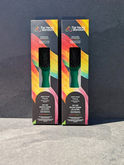 Two retail packaging boxes for The Neuro Standard's sensory-friendly hairbrush, featuring a black box with a vibrant rainbow design.