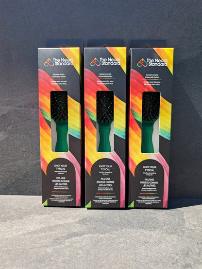 Three retail packaging boxes for The Neuro Standard's sensory-friendly hairbrush, featuring a black box with a vibrant rainbow design.